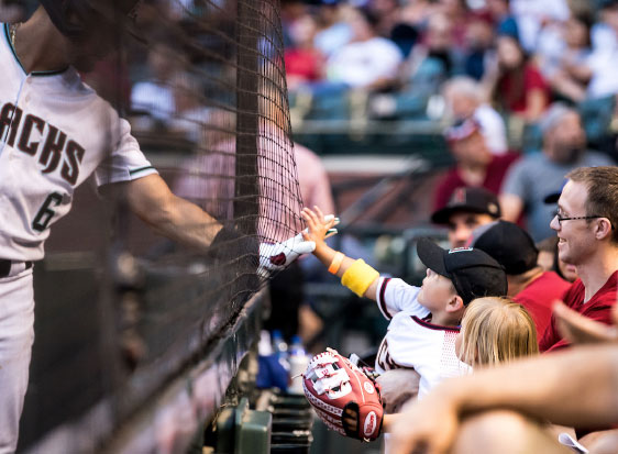 A child reaches through a net to touch hands with a player