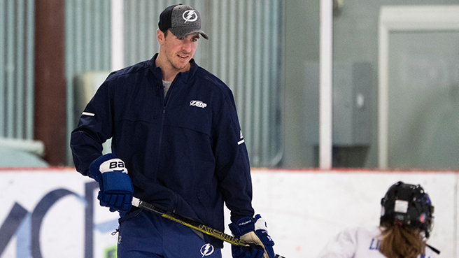 A hockey player instructing a young player