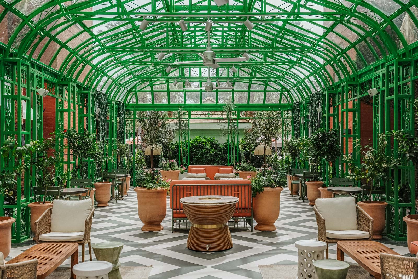 A room with a glass ceiling has several seating areas and plants.
